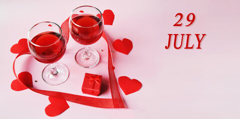 calendar date on light background with two glasses of red wine, red gift box and red hearts with copy space. July 29 is the twenty-ninth day of the month