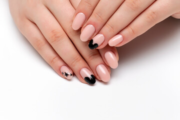 Exclusive manicure. Beige, nude manicure with painted black stars and a silhouette of a mouse on long oval nails close-up on a white background.