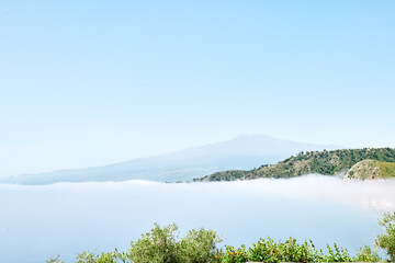 View of the gulf of Giardini Naxos covered by thick fog with Mount Etna in background. Beauty in Sicily as a tourist attraction. Season on mediterranean sea. Ionian sea.