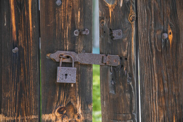 old wooden gate with rusty padlock. Background