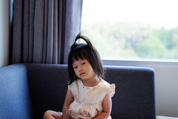 Asian baby girl has angry face,sit on sofa in her room.