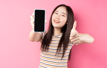 Naklejka premium Young Asian woman using smartphone on pink background