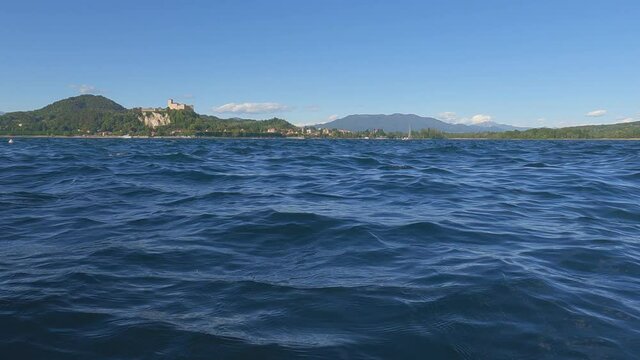 Surface level view of small boat sailing on Maggiore lake in Italy. Zoom in slow-motion