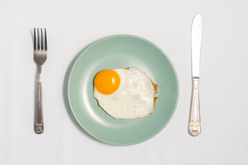 fried eggs on a blue plate with a fork and knife, flat lay
