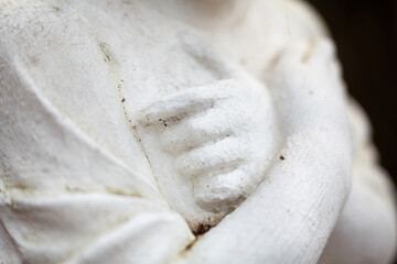 Hands on the chest. Old sculpture.