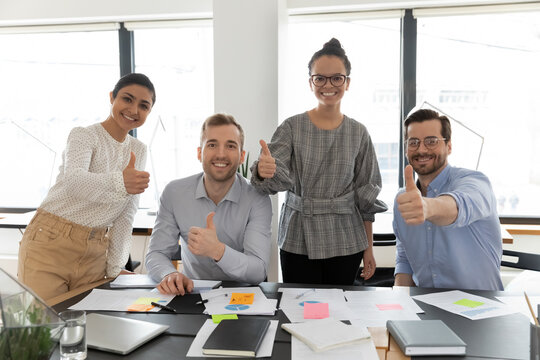 Portrait of happy diverse colleagues employees group showing thumbs up, standing in boardroom, looking at camera, excited businesspeople recommending best corporate service, career opportunities
