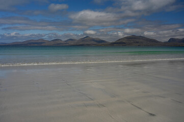 Shoreline at Luskentyre beach, Isle of Harris, Scotland. Sunny day with blue sky and clouds. White...