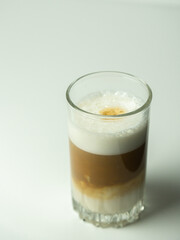 Glass of latte coffee on light background