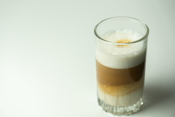 Glass of latte coffee on light background