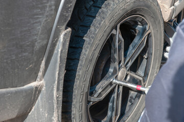 Fototapeta premium Wheel replacement on the road by the driver. Replacing summer tires with winter tires with a handy wrench by a mechanic after balancing the wheels in close-up