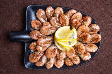 fried shrimp with lemon on a black plate view from top
