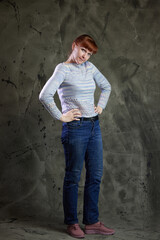 Portrait of Caucasian woman posing in full growth in jeans in studio on gray background. High resolution photos