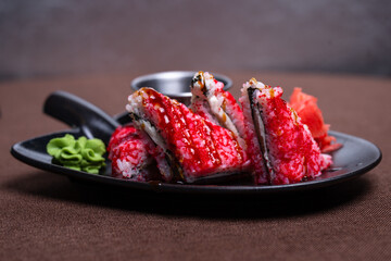 sushi from red rice with fish on a black plate