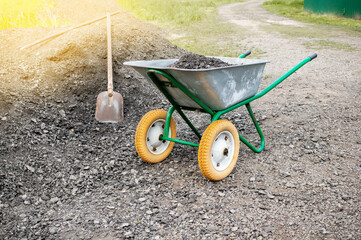 wheelbarrow with a shovel and gravel. as part of a construction project, a man is transporting...