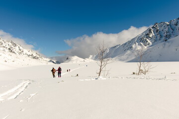 Tourists on the frozen large pond in the valley of the Five Ponds. Winter Tatra Mountains, mountain landscape. January in the Valley of Five Ponds in the Tatra Mountains.