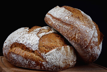 Two loaves of rustic bread on a wooden board. Homebaked bread .