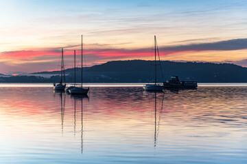 Sunrise waterscape with boats, light cloud and fog