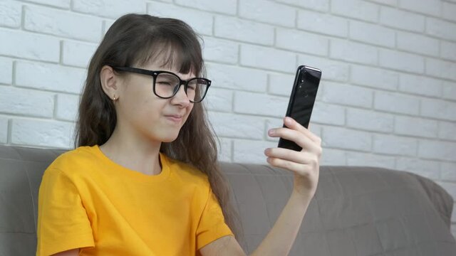 Girl feel tired eyes. A young girl in glasses hold her telephone and try to read something.