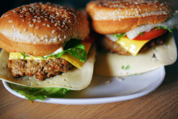 Photos of homemade burgers. Steak and white bun with sesame seeds, cheese and cabbage, tomatoes. Homemade food.