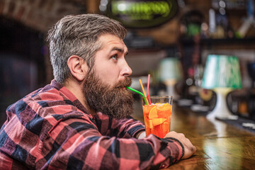 Tropical alcoholic fresh cocktail. Barman in pub or restaurant. Bearded man cocktail. Portrait man, drinking orange juice. Bearded man drink cocktails