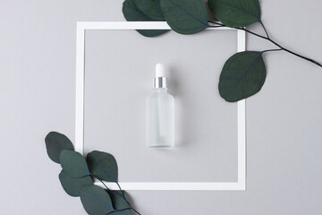 White frame with cosmetic bottle on grey background. Flat lay.