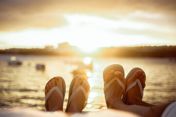 Legs of a couple against the background of the ocean and the sea, beautiful sunset and travel,...