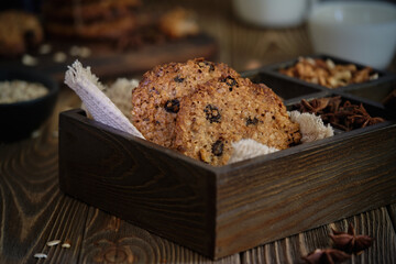 Delicious and flavorful oatmeal cookies with nuts, raisins and spices with a cup of milk on old wooden table