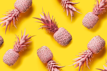 Pattern with pink painted pineapples isolated on a yellow background. Creative summer food concept. Pop art aesthetic with tropical vibes. Flat lay, top view.