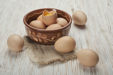 Bowl of raw chicken eggs on the wooden background