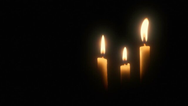 Three burning candles against a black background with copy space.