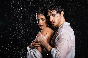 wet sexy romantic couple passionately hugging on black background with side lighting on black background