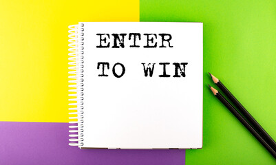 Minimal work space : sketchbook on the colorful background with ENTER TO WIN text