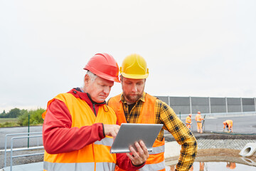 Bauleiter und Bauarbeiter auf der Baustelle mit Tablet PC