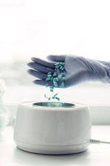 Depilatory master puts wax capsules into the wax melter, close-up