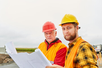 Zwei Bauarbeiter mit Bauplan auf einer Baustelle