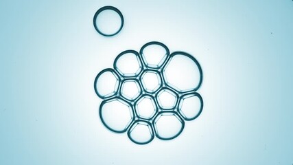 Small clear bubble joins to bubble cluster of twelve another ones against cyan background | Shot of skin care cream ingredients for skin hydration concept