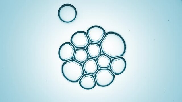 Small clear bubble joins to bubble cluster of twelve another ones against cyan background | Shot of skin care cream ingredients for skin hydration concept