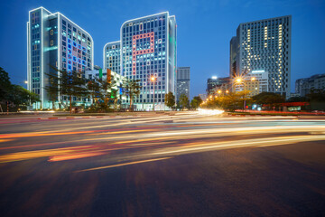 Cityscape of a street in Hanoi with high buildings during sunset time with blurred cars running on street