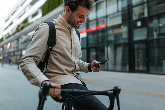 Happy cyclist in the city using phone
