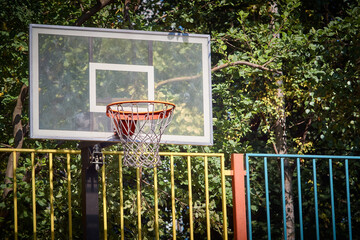 Basketball hoop on a playground outdoor and green trees on background