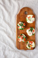 Homemade Egg White Breakfast Cups with Spinach and Tomato on a rustic wooden board, top view. Flat lay, from above. Space for text.