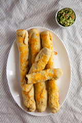Homemade Cheesy Taco Breadsticks with Guacamole, overhead view. Flat lay, from above, top view.