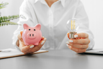 Female hand holding a light bulb above the table