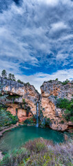 Idyllic waterfall with colorful pond and cloudy sky