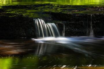 Cascading waterfall cascades in Estonia in green light at summertime