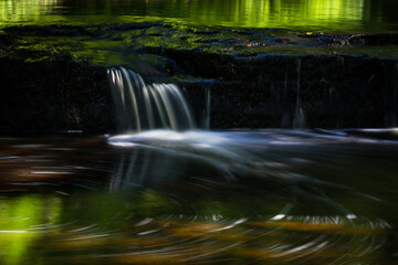 Cascading waterfall cascades in Estonia in green light at summertime