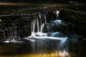 Cascading waterfall cascades in Estonia in green light at summertime