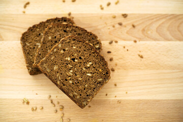 whole grain brown bread, three slices fanned out on wooden surface, high angle view, copy space