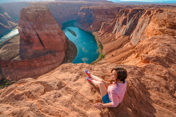 Rear view of a young woman enjoying a view of the incredible Horseshoe Bend, the horseshoe meander...