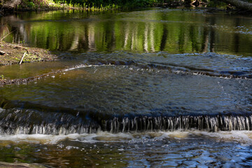 Cascading waterfall cascades in Estonia in green light at summertime